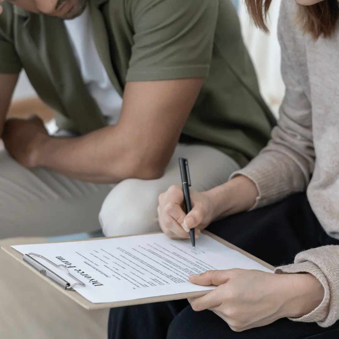 A picture of a man and woman getting an uncontested divorce as they sign a divorce decree.